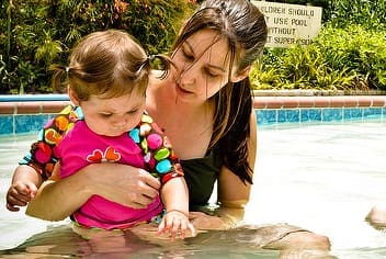 Woman holding little girl in swimming pool