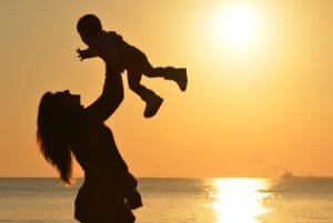 Adult holding baby at beach