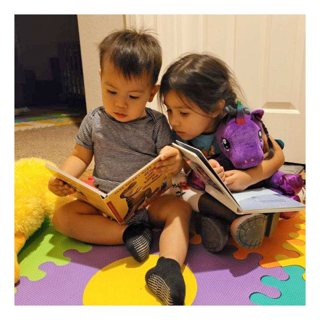 two cute toddlers sharing their books with each other